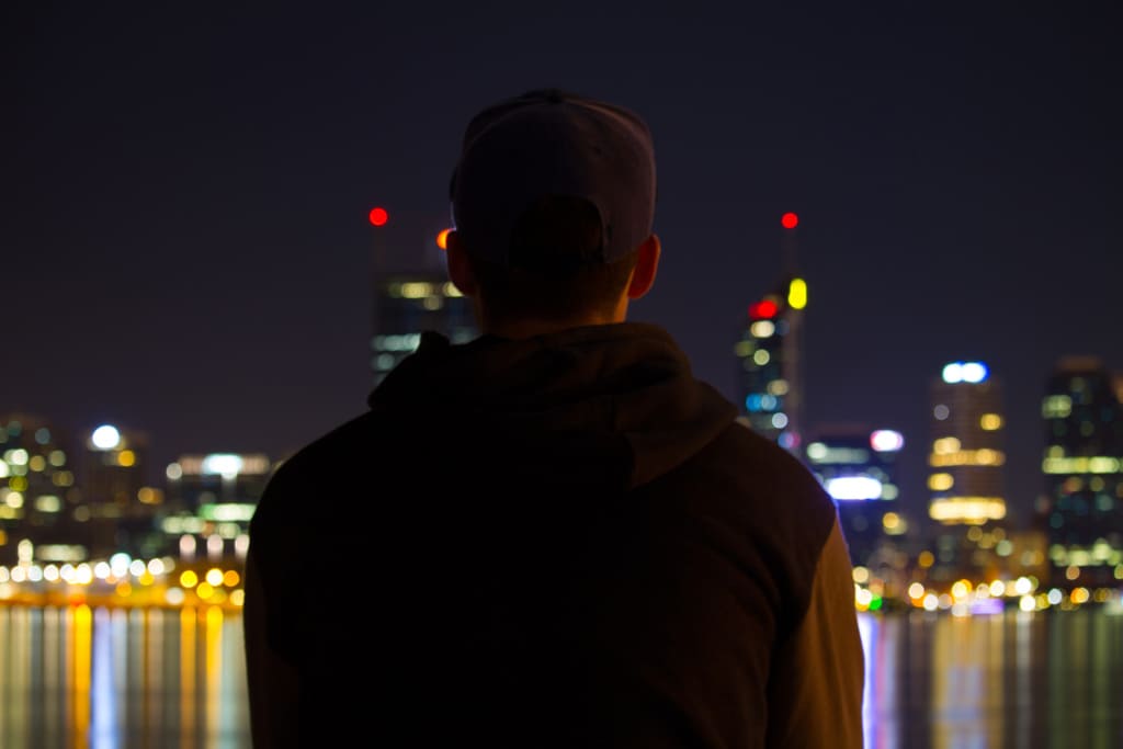 Hombre contemplando a la distancia la ciaudad por la noche solitario